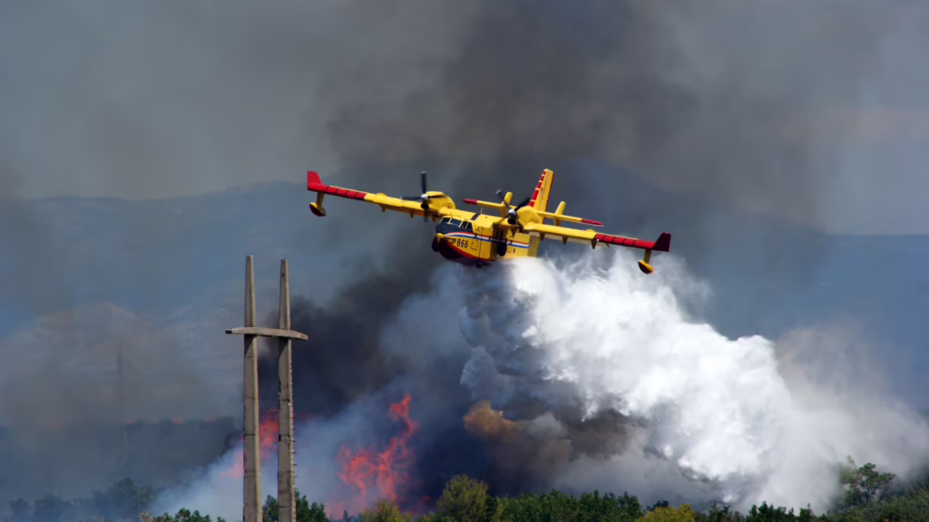 A Canadair water bomber makes a drop on an advancing fire front.